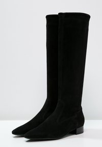 Zwarte suede over-de-knie laarzen met een spitse neus en een kleine blokhak. Gladde textuur met minimale zichtbare stiksels.