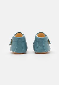 Leder Schuhe in einem hellblauen Farbton mit einer strukturierten Oberfläche, ausgestattet mit einer Rückenschlaufe und einer weichen Sohle für Flexibilität.