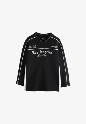 Sort langærmet skjorte med hvide sidepaneler, tekst "Los Angeles Limited Edition," "No. 91/B," "Code 0012," og "Est. 1992" foran.