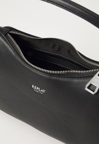 Black leather handbag with a zippered opening, inner pockets, and silver hardware. Features a small "REPLAY" logo on the front.