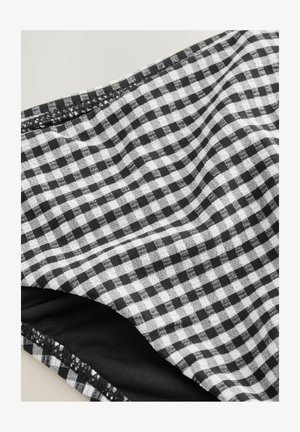 Țesătură gingham alb-negru cu o suprafață texturată, având o căptușeală netedă neagră la margine și un finisaj de cusătură curat și precis.