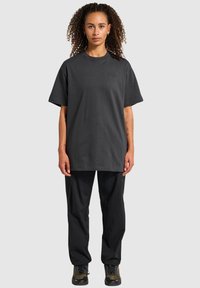 Mörkgrå överdimensionerad t-shirt i bomull med rundad hals och korta ärmar, med en diskret logotypdetalj på bröstet, i kombination med svarta byxor.