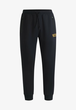 Schwarze Jogginghosen aus glattem Material, mit zwei seitlichen Reißverschlusstaschen und einem Kordelzugbund, verziert mit einem goldenen Logo-Detail.