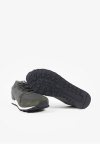Baskets sportives avec une combinaison de maille grise et de suede vert foncé. La semelle en caoutchouc noir texturé possède une adhérence à motifs pour la traction.