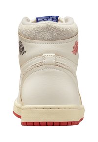 Weiße High-Top-Sneaker mit Obermaterial aus Wildleder und Leder. Rote Akzente an der Sohle, Logo auf der Ferse und blauer Aufnäher am Kragen. Strukturierte Details.