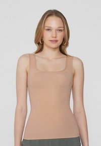 Nude upnutý top na ramínka se čtvercovým výstřihem a tenkými ramínky, vyrobený z hladkého elastického materiálu, navržený pro štíhlou siluetu.