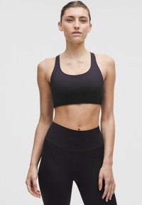 Svart sportbh med breda band och rundad halsringning, matchad med högmidjade svarta leggings, tillverkade av ett mjukt och stretchigt material.