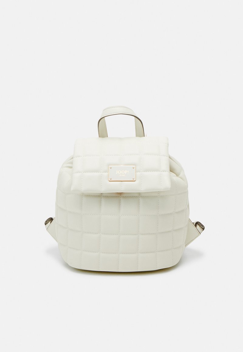 Sac à dos blanc matelassé avec un rabat, comprenant une plaque logo dorée et des bretelles réglables. Matériau lisse avec une forme structurée.