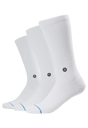 Trois paires de chaussettes blanches à texture côtelée, avec un logo noir au niveau de la cheville et un accent bleu au niveau des orteils.