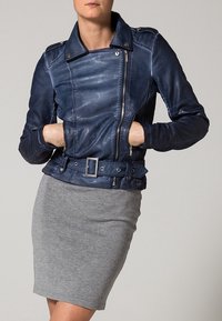 Giacca in pelle blu navy con un design aderente, chiusura a zip asimmetrica, vita con cintura e texture a coste sulle maniche.