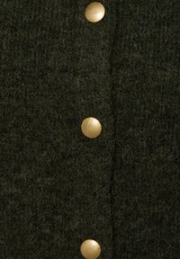 Cardigan en tricot vert foncé avec une finition texturée, doté de grands boutons dorés à l'avant. La vue de près met en évidence le détail du tissu.