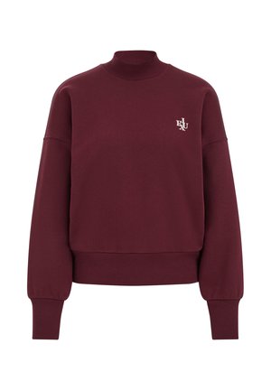 Sudadera burdeos con un cuello alto, hombros caídos, puños acanalados y un pequeño logo bordado en el pecho. Textura de tela suave.