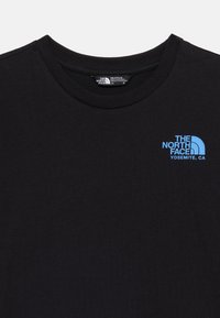 Μαύρο μπλουζάκι με στρογγυλή λαιμόκοψη και μικρό φωτεινό γαλάζιο λογότυπο «The North Face Yosemite, CA» στο πάνω αριστερό μέρος του στήθους, με ετικέτα μεγέθους μέσα στον γιακά.