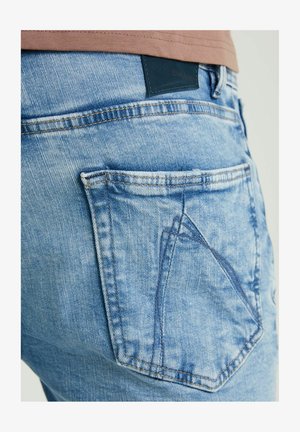 Lichtblauwe denim spijkerbroek met een driehoekig achterzakontwerp, vervaagde textuur en een zwart leren merkpatch op de taille.
