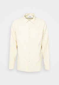 Jasnokremowa, długorękawowa koszula na guziki wykonana z miękkiego materiału, z kołnierzykiem, pojedynczą kieszenią na piersi i luźnym krojem.