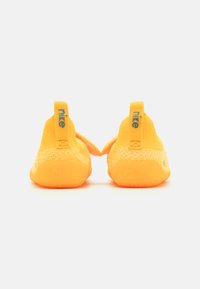 Gelbe Nike-Schuhe mit einem strukturierten Strick-Obermaterial und Gummisohle, ausgestattet mit einer Zuglasche und blauen Logo-Akzenten an der Ferse.