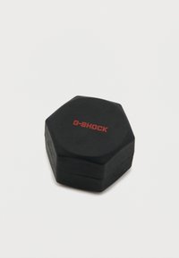 Melna sešstūra forma iepakojums ar matētu virsmu. Augšpusē ir pacelts sarkans "G-SHOCK" logotips. Gluda tekstūra, izturīgs dizains, kompakts izmērs.