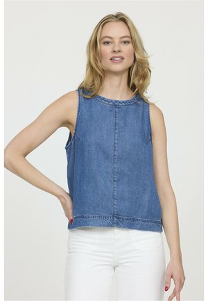 Haut en denim sans manches de bleu moyen avec un col rond, un ourlet brut et des coutures visibles. Associé à un jean blanc.