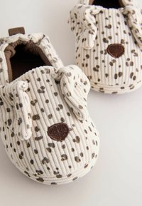 Chaussures souples pour bébé en tissu crème et marron à pois, dotées d'oreilles tombantes et d'un nez brodé marron ressemblant à la face d'un chien.