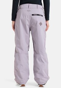 Light purple snow pants with a loose fit, featuring embroidered branding on the back pockets and visible seams at the waistband.