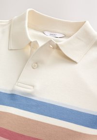 Polo color crema con colletto a tre bottoni. Presenta strisce orizzontali in blu, rosa e beige. Realizzata in tessuto a maglia liscia.