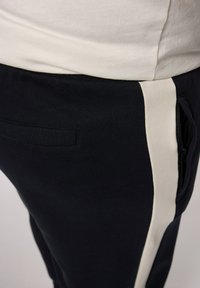 Marine joggers met een contrasterende off-white zijstreep, gemaakt van een katoenmix. Beschikt over een zijzak en een ontspannen pasvorm bij de taille.