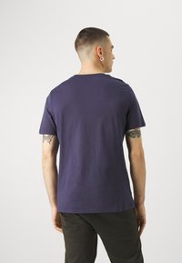 Mørkeblå T-skjorte med korte ermer og rund hals, laget av myk bomull. Har standard passform og minimal design uten mønstre.