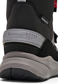 Sort atletiksko med grå detaljer, der har en struktureret hælkappe, glat mellemsål og hummel-branding. Fremstillet af syntetiske materialer.