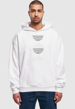Valge kapuutsiga sweatshirt, millel on ees tasku ja graafiline disain, kus on kolm ümmargust kuju halli tooni, millel on horisontaalsed jooned.