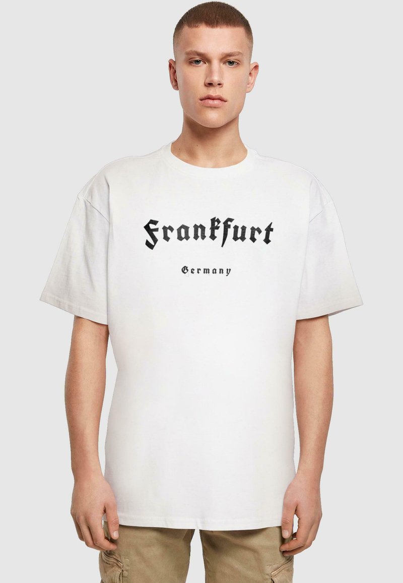 Hvit bomulls T-skjorte med svart gotisk stiltekst som leser "Frankfurt Tyskland" over brystet, med en løs og avslappet passform.