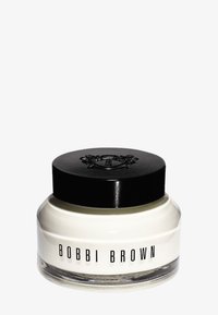 Bobbi Brown-krem i en klar glasskrukke med svart lokk. Har preget logo på toppen og et jevnt, hvitt produkt synlig inni.
