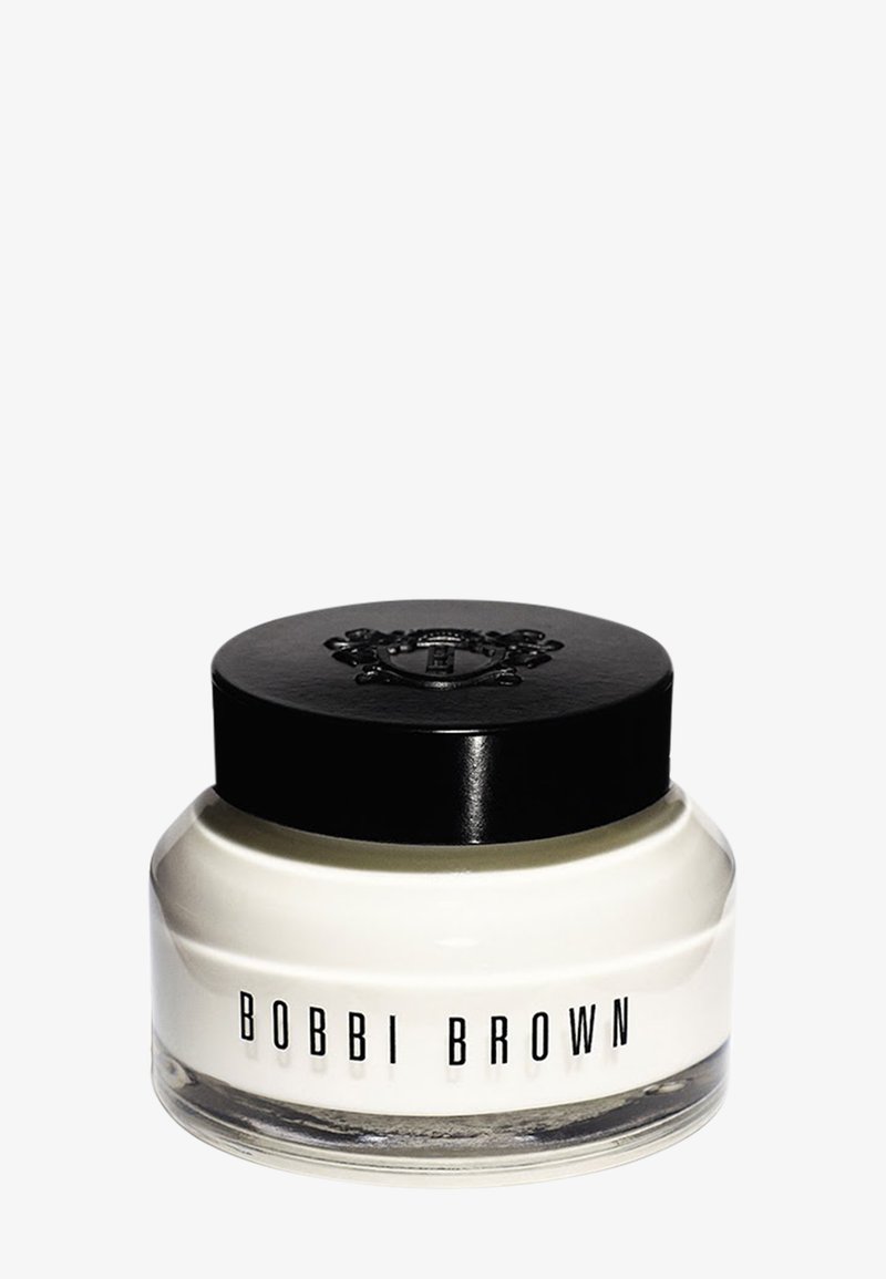 Bobbi Brown-krem i en klar glasskrukke med svart lokk. Har preget logo på toppen og et jevnt, hvitt produkt synlig inni.