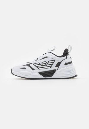 White athletic shoe with black accents, mesh upper, chunky sole, distinctive logo design, and textured overlays. Features lace-up closure and heel tab.