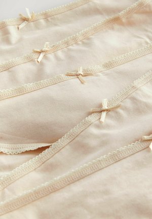 Beżowa tkanina z subtelną teksturą i dekoracyjnym koronkowym wykończeniem, z małymi kokardkami wzdłuż krawędzi. Starannie ułożona z gładkimi fałdami.