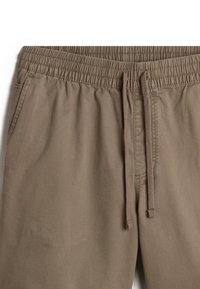 Světle hnědé šortky s elastickým pasem a nastavitelným stahovacím šňůrkou. Mají boční kapsy a hladkou, lehkou texturu látky.