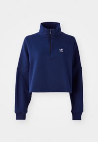 Sudadera recortada de color azul marino con media cremallera, cuello alto y mangas largas. Presenta un pequeño logo blanco en el pecho. Textura suave.