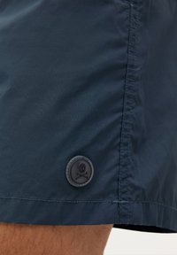 Shorts de bain navy en tissu léger et lisse, dotés d'un bouton en caoutchouc avec un motif de skull et os croisés sur la couture latérale.
