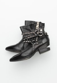 Svarta läderankelstövlar med spetsiga tår, prydda med silvernitar och remmar. Har en sidogdragkedja och en låg blockklack.