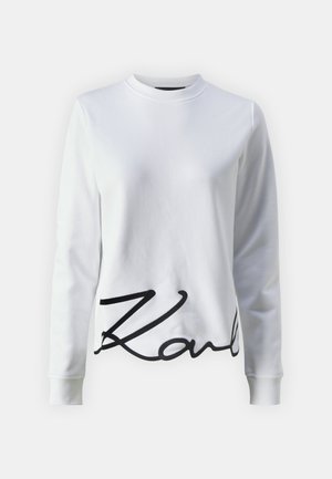 Sudadera blanca con cuello redondo, mangas largas y un gran logo en escritura negra "Karl" en la parte frontal. Fabricada en un tejido suave.