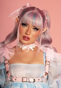 Abito azzurro pastello con maniche in tulle arricciato, spalline in pelle rosa con accessori a forma di cuore, choker in pizzo e capelli rosa con riflessi lavanda.