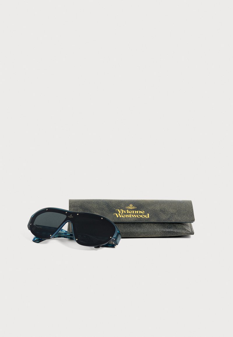 Lunettes de soleil oversize foncées avec montures bleues à côté d’un étui en cuir noir Vivienne Westwood avec logo doré sur fond blanc.