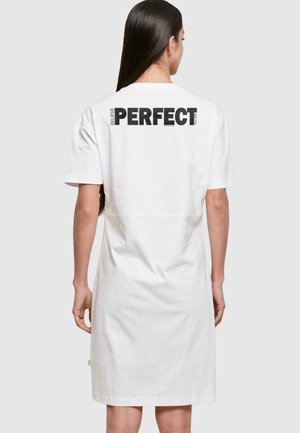 Balta medvilninė t-shirt su trumpomis rankovėmis, su juodu tekstu „TIKĖK, KAD ESI TOBULAS“ ant nugaros, laisvas prigludimas, iki kelių ilgio.