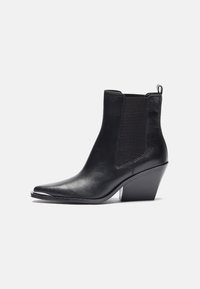 Botas de cuero negro hasta el tobillo con punta afilada, paneles laterales elásticos y un tacón cuadrado. El acabado es suave con un diseño elegante.