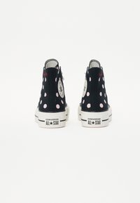 Svarta högstövlar med rosa pricker, Converse All Star-logotyp och en vit gummisula. Har en snörningsdesign och vadderad krage.