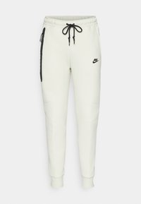 Vita Nike sweatpants med elastisk midja, dragsko, sidofickor med dragkedja och svarta logodetaljer. Mjuk tyg med ribbad mudd.