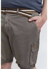 Khaki cargo shorts med struktureret stof, sidelomme og brunt, sort og hvidt vævet bælte. Har et lille mærke på siden.