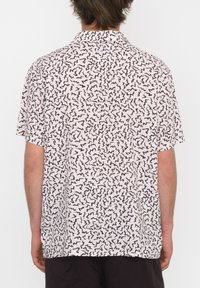 Kurzarmshirt mit rosa Hintergrund, das ein schwarzes, abstraktes Zickzack-Muster zeigt. Der Stoff wirkt leicht und atmungsaktiv.