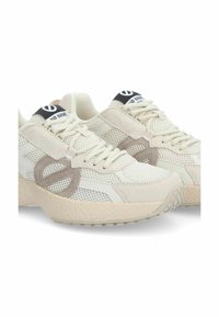 Weiße Netzsneaker mit beigefarbenen Wildlederakzenten, strukturierten Sohlen und einem schwarzen Etikett auf der Zunge mit dem Markennamen.