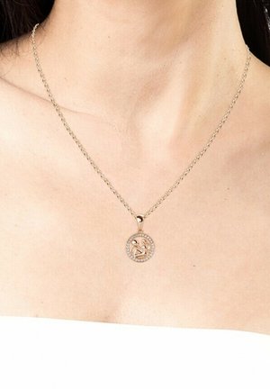 Gouden halsketting met een ronde hanger met een centraal ontwerp omringd door kleine heldere stenen. De ketting heeft een klassiek schakelpatern.