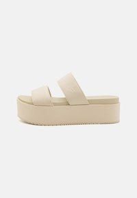Sandali platform beige con due ampie cinghie, realizzati in tessuto, con suola texturizzata e dettagli logo sottili. Design liscia e minimalista.